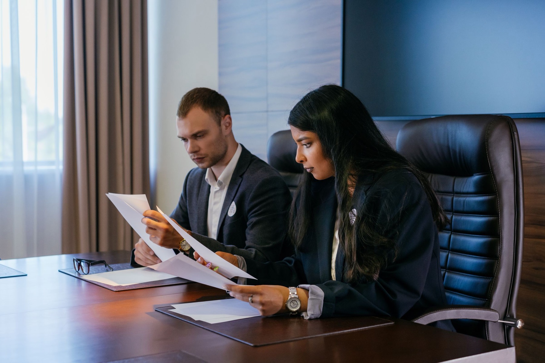 Two colleagues reading printed documents at a boardroom table