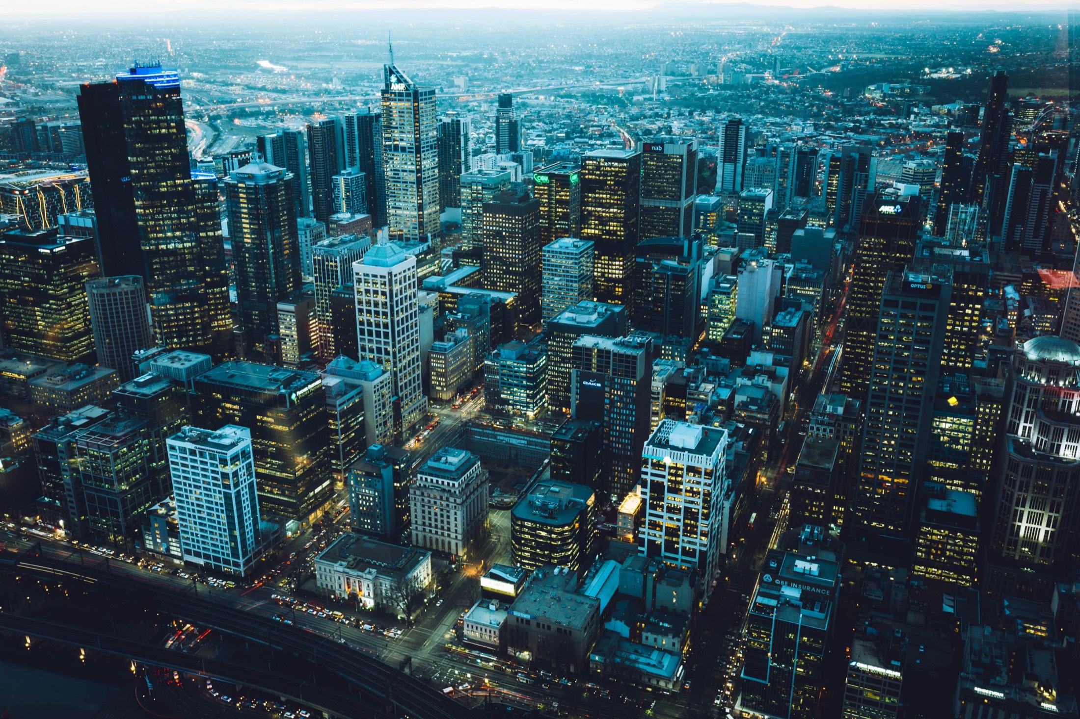 Aerial view of a dense city at blue hour with lit streets below