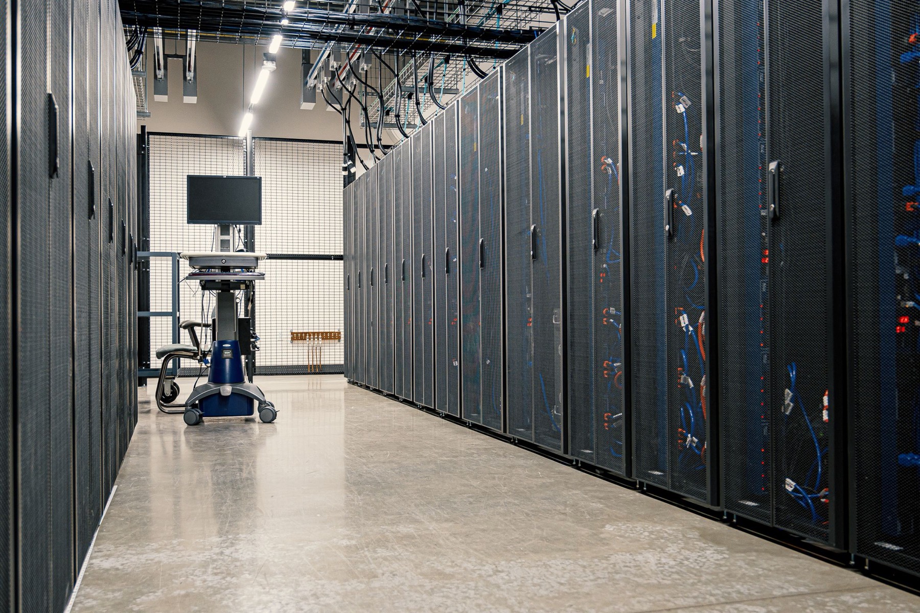 Corridor between rows of black server cabinets in a data centre